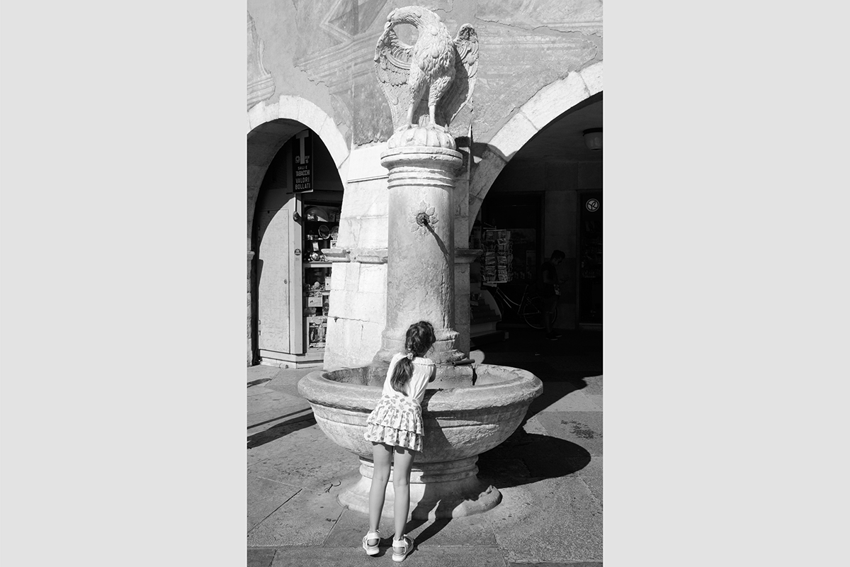 A girl drinking at a fountain, Piazza Duomo, Trento, Italy, 2016.  Photograph by David Rowley